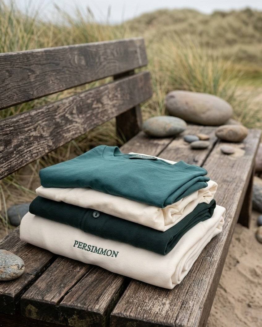 Stack of folded clothes on a wooden bench with a natural background