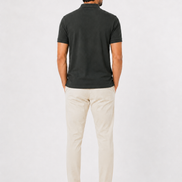 Man wearing a dark green polo shirt and beige pants on a white background