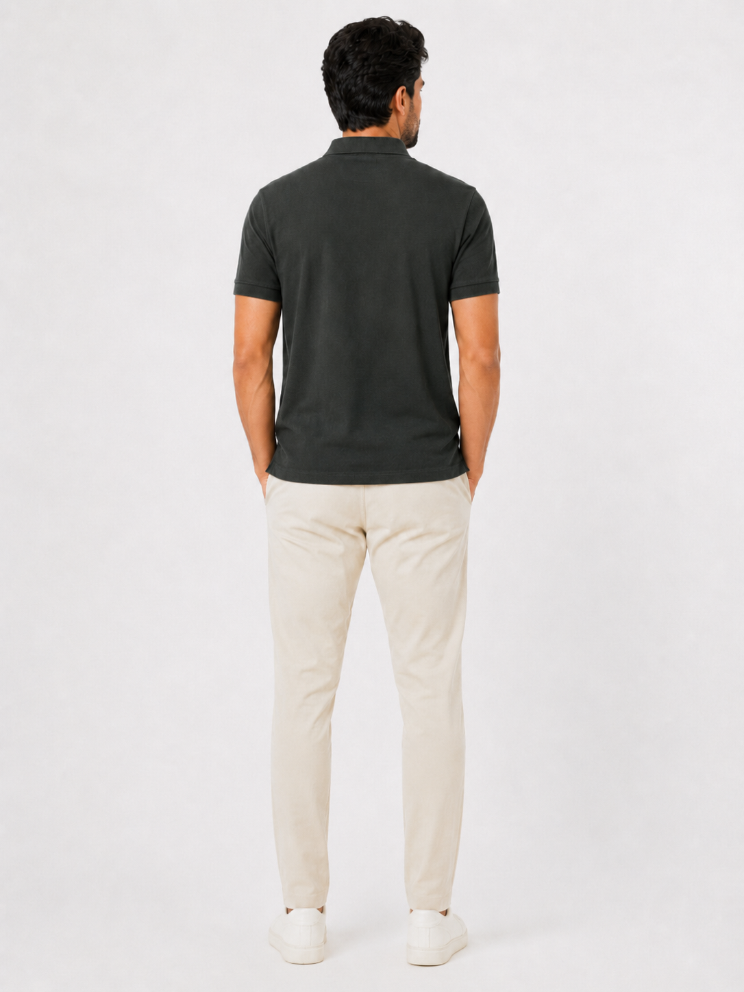 Man wearing a dark green polo shirt and beige pants on a white background