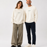 Two people wearing matching cream sweatshirts with a logo on a white background