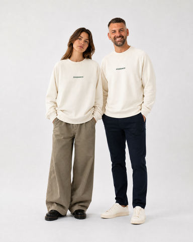Two people wearing matching cream sweatshirts with a logo on a white background