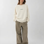 Person wearing a cream sweatshirt and pants on a white background