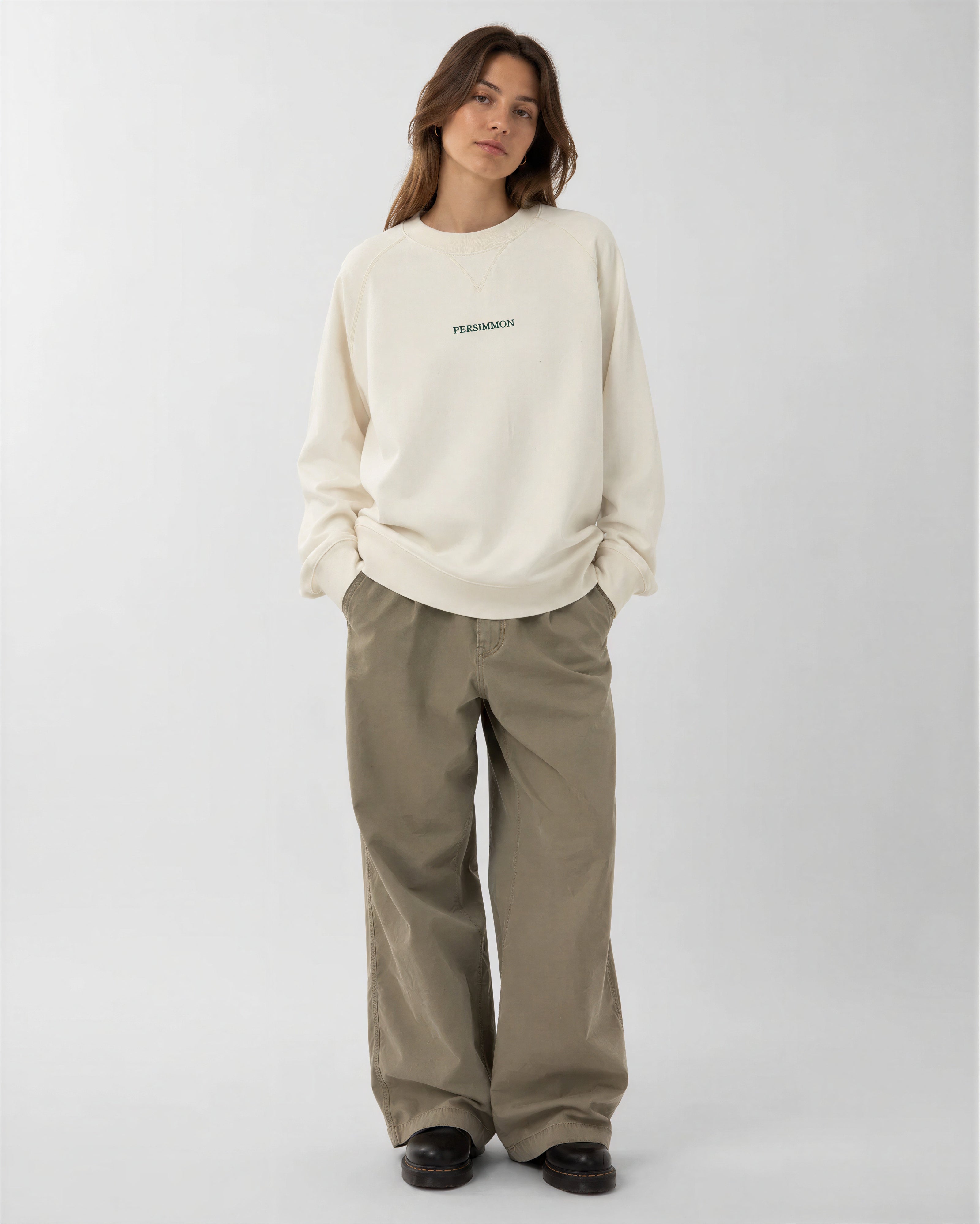 Person wearing a cream sweatshirt and pants on a white background