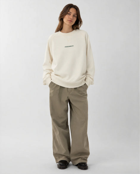 Person wearing a cream sweatshirt and pants on a white background