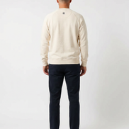 Man wearing a cream sweater and navy pants on a white background