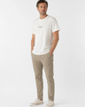 Man wearing a cream t-shirt and beige pants on a white background