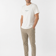 Man wearing a cream t-shirt and beige pants on a white background