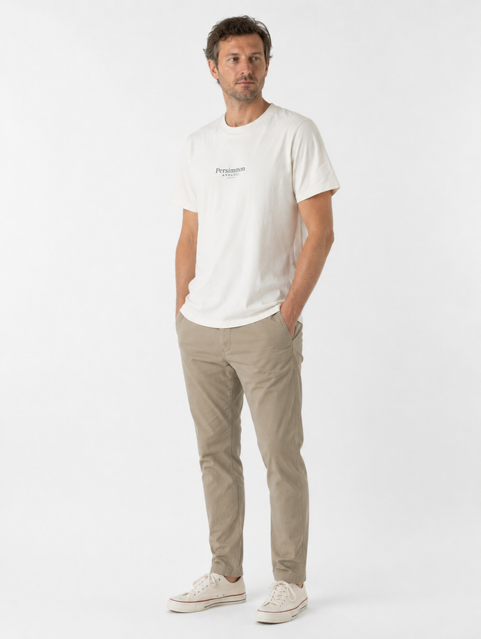 Man wearing a cream t-shirt and beige pants on a white background