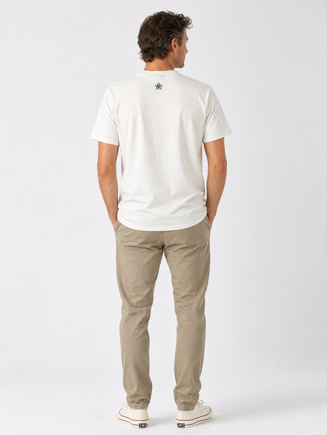 Man wearing a cream t-shirt and beige pants on a white background