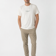Man wearing a cream t-shirt with Persimmon Apparel branding and beige pants on a white background