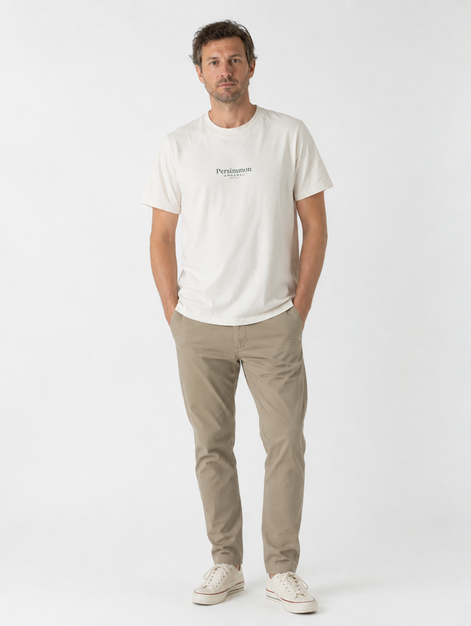 Man wearing a cream t-shirt with Persimmon Apparel branding and beige pants on a white background