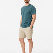 Man wearing a green t-shirt and beige shorts on a white background