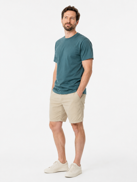 Man wearing a green t-shirt and beige shorts on a white background