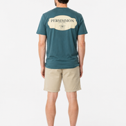 Man wearing a green t-shirt with Persimmon logo and beige shorts on a white background