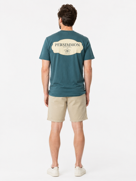 Man wearing a green t-shirt with Persimmon logo and beige shorts on a white background