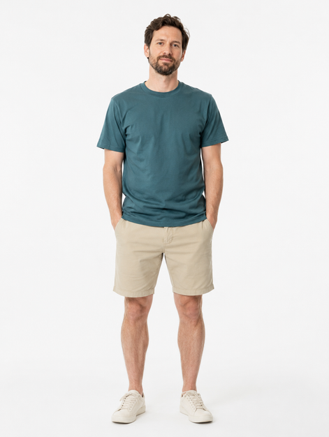 Man wearing a green  t-shirt and beige shorts on a white background