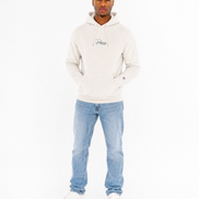 Man wearing a cream hoodie and light blue jeans on a white background