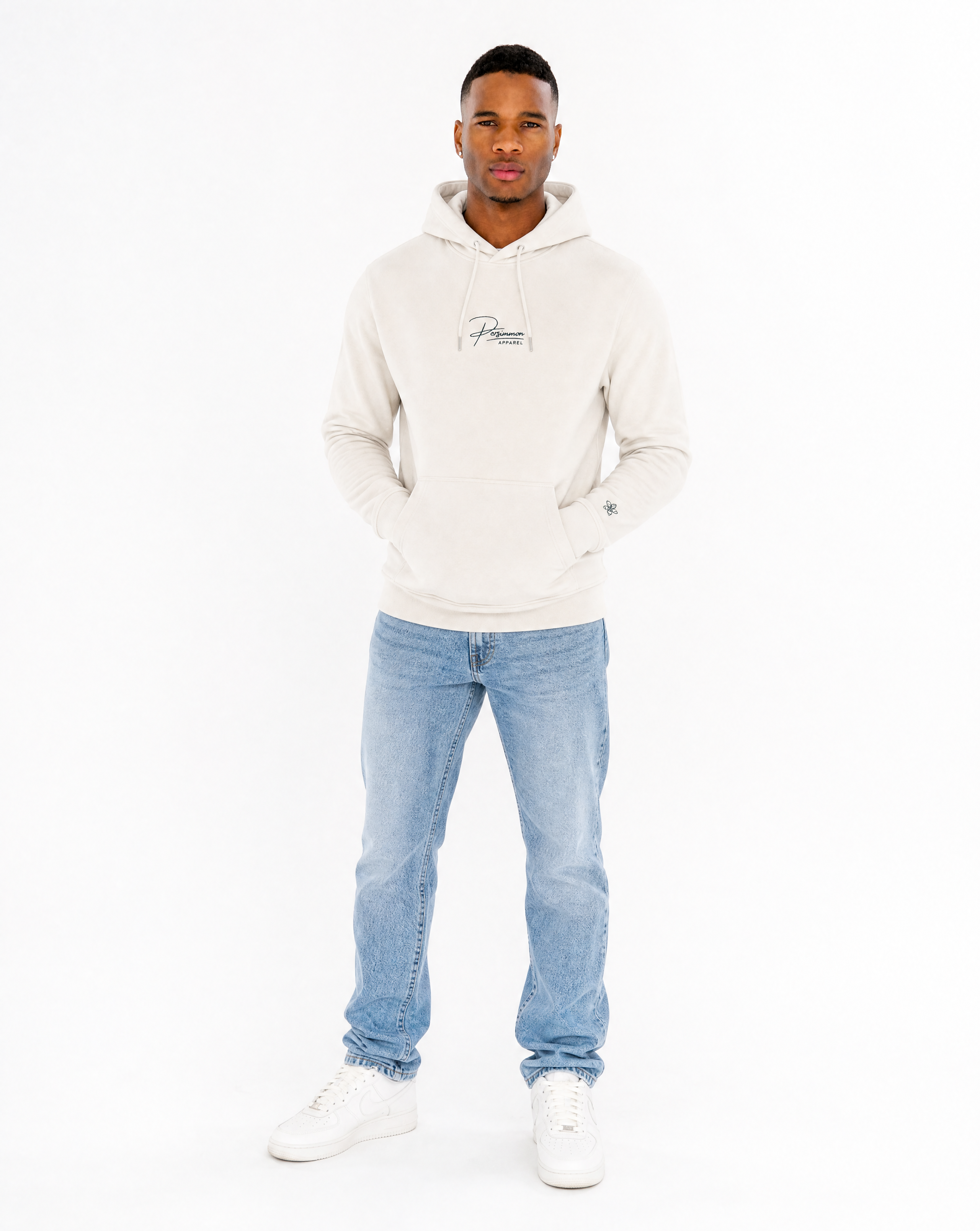 Man wearing a cream hoodie and light blue jeans on a white background