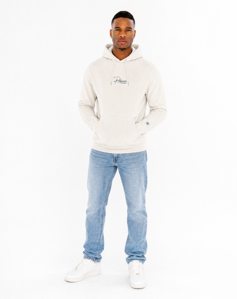 Man wearing a cream hoodie and light blue jeans on a white background