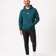 Man wearing a green hoodie with a Persimmon logo, black pants, and white shoes on a white background