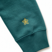 Green hoodie sleeve with a yellow embroidered Persimmon emblem design on a white background