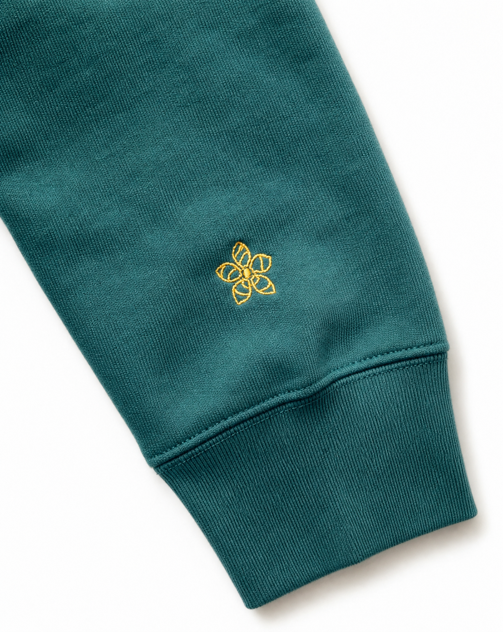 Green hoodie sleeve with a yellow embroidered Persimmon emblem design on a white background