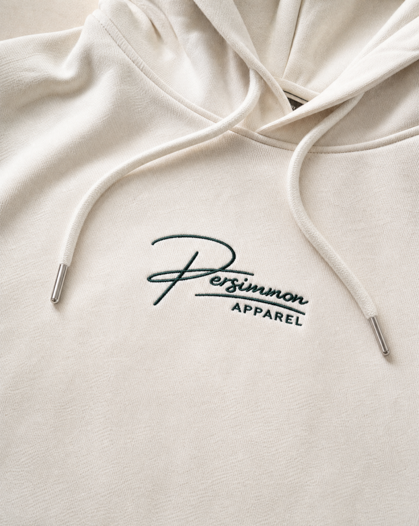 Cream hoodie with 'Persimmon Apparel' logo on a white background