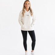 Woman wearing a cream hoodie with Persimmon logo, black leggings, and white trainers on a white background