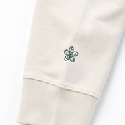 Close-up of a cream hoodie with a small embroidered Persimmon emblem design on a white background