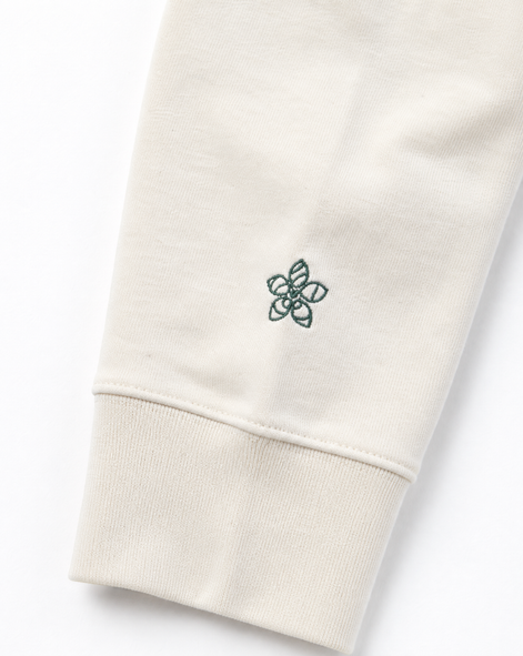 Close-up of a cream hoodie with a small embroidered Persimmon emblem design on a white background